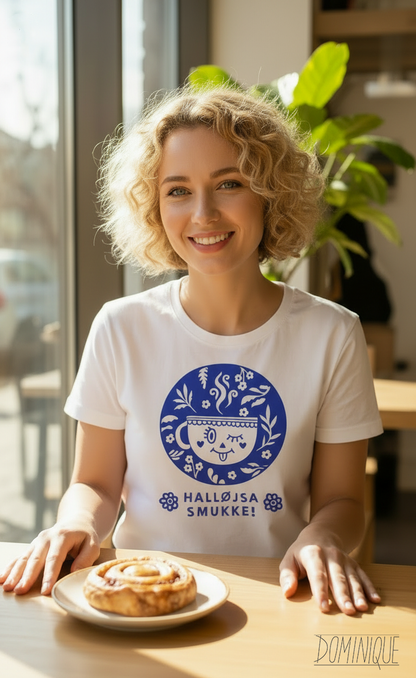Woman wearing a white t-shirt with a blue design, sitting at a table with a pastry.